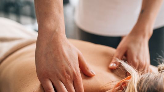A woman receiving a back, shoulder and neck massage on a treatment couch
